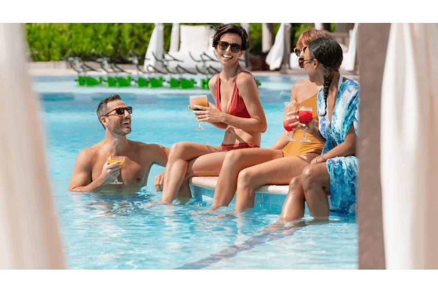 Grupo de amigos con cocteles en una piscina de Hilton resort.
